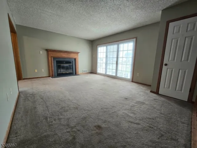 a view of an empty room with a fireplace and a window