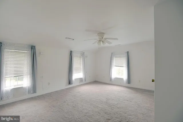 a view of empty room with window and ceiling fan