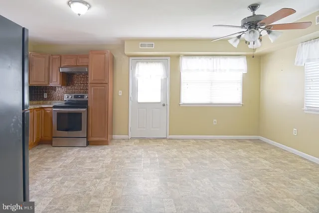 an empty room with a kitchen and a stove top oven