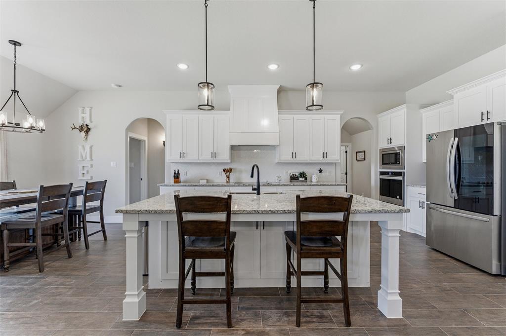 3020 Westfork Way Springtown, TX 76082 - Photo 14 of 40 a kitchen with stainless steel appliances kitchen island granite countertop a table chairs and a refrigerator