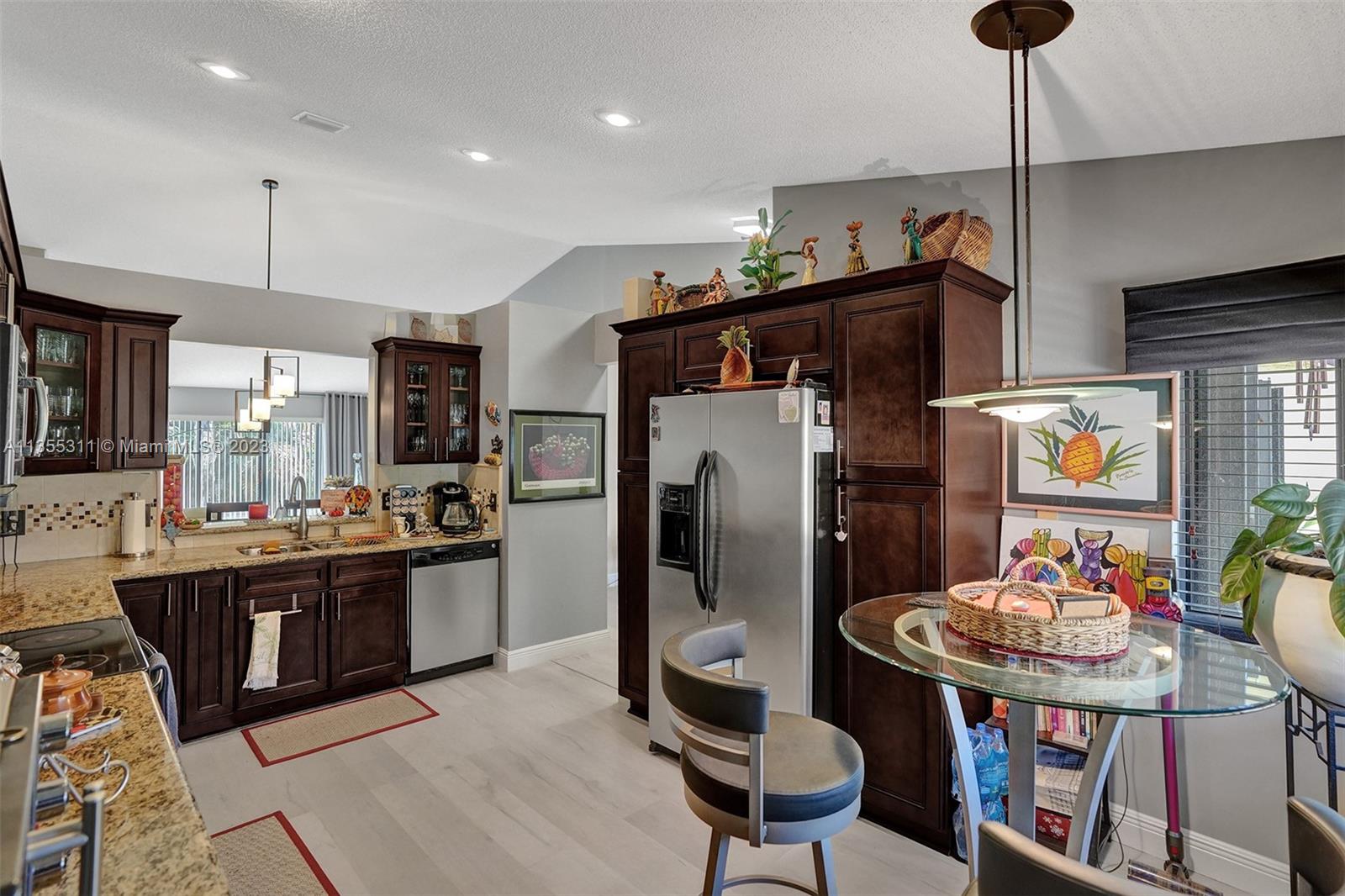 Tamarac Tamarac, FL 33321 - Photo 31 of 49 a kitchen with stainless steel appliances kitchen island granite countertop a dining table and chairs with wooden floor