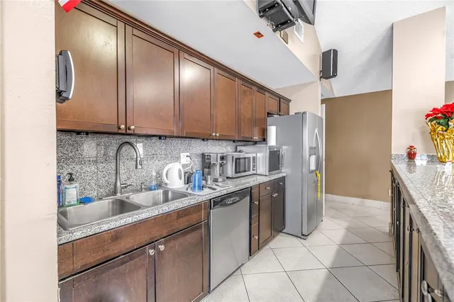 a bathroom with stainless steel appliances granite countertop a sink and a refrigerator