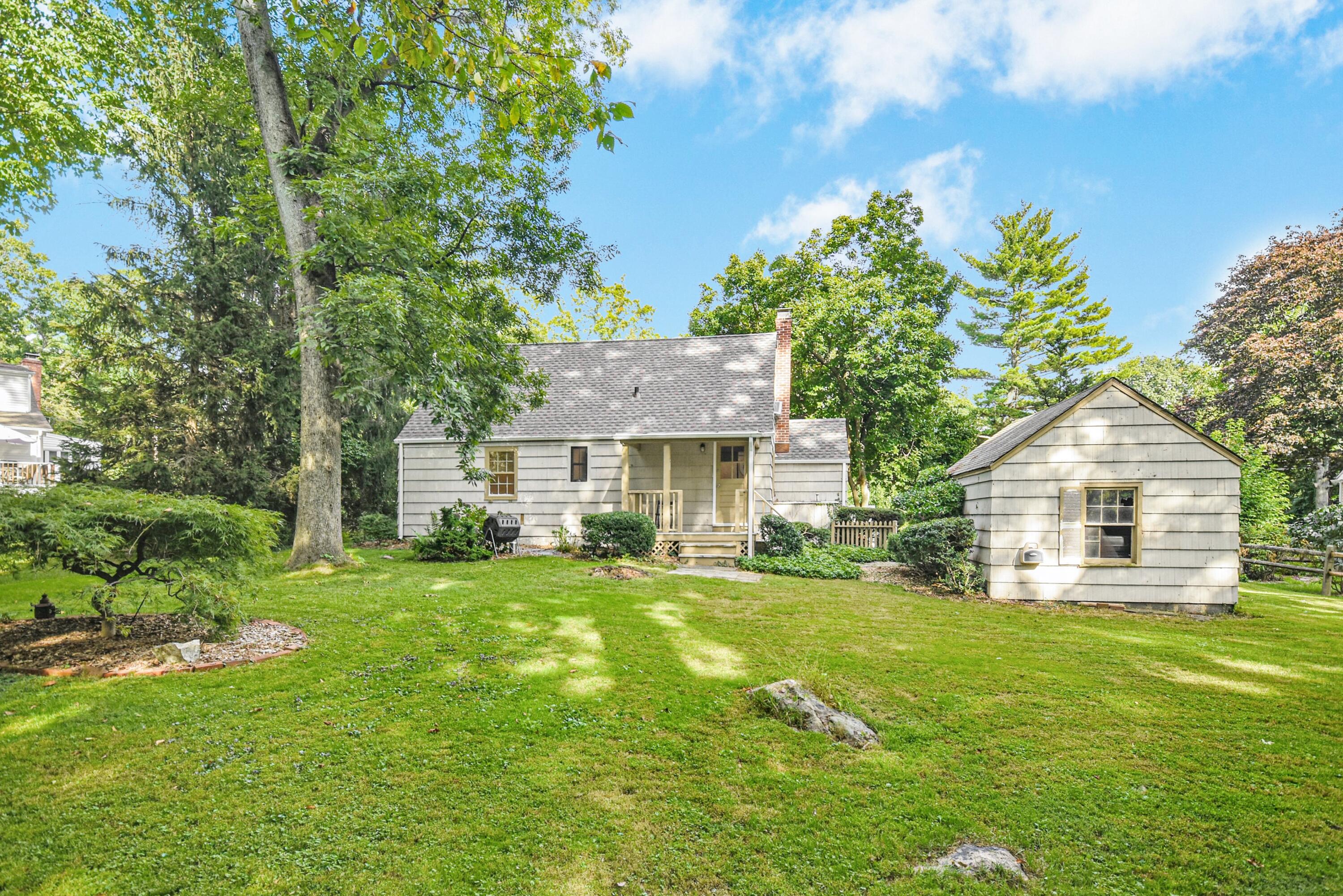 16 Burchard Lane Rowayton, CT 06853 - Photo 20 of 22 a front view of a house with a garden and trees