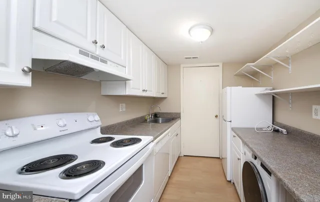 a kitchen with granite countertop a sink a stove and refrigerator
