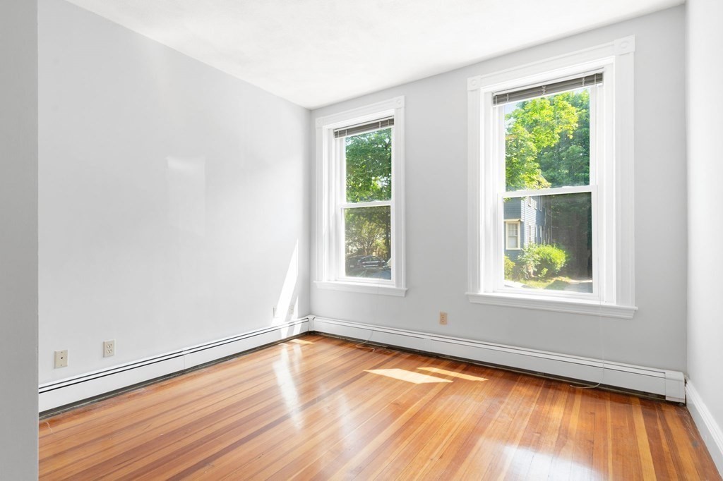 815 Centre Street, Unit 1 Boston, MA 02130 - Photo 14 of 30 an empty room with wooden floor and windows