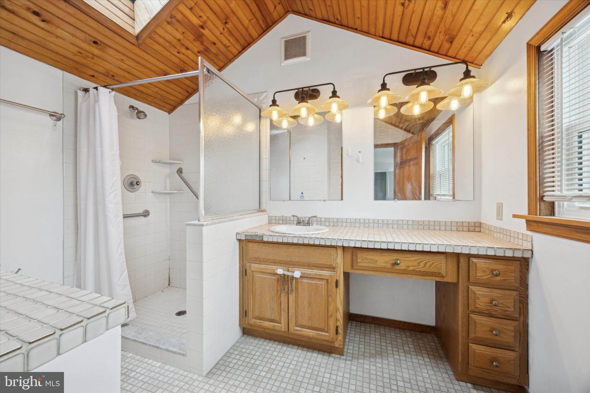 606 West Springfield Road Springfield, PA 19064 - Photo 14 of 25 a bathroom with a double vanity sink a mirror and a bathtub