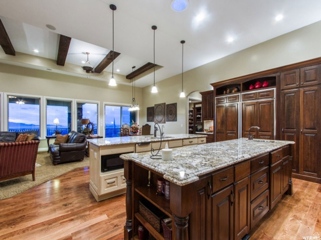 4378 Foothill Drive Bountiful, UT 84010 - Photo 6 of 46 Open-concept kitchen and living area featuring dual islands with granite countertops, rich wood-finish flooring, and exposed ceiling beams