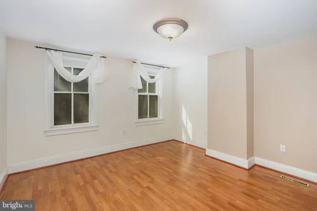 a view of an empty room with a window and wooden floor
