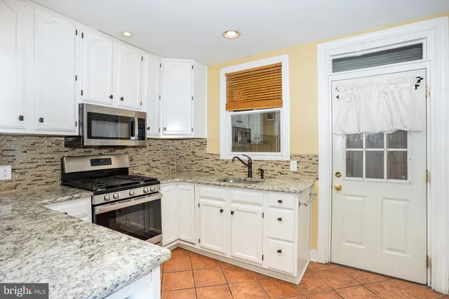 a kitchen with granite countertop a stove sink and microwave