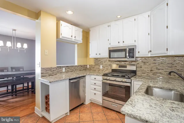 a kitchen with granite countertop a stove top oven and cabinets