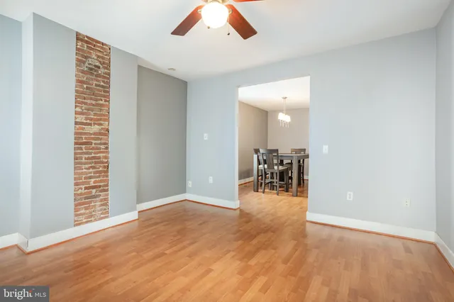 an empty room with wooden floor and a way to kitchen