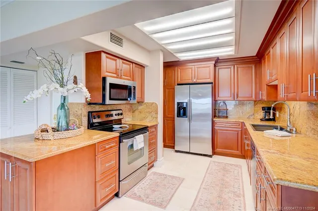 a kitchen with stainless steel appliances granite countertop a sink dishwasher a stove a refrigerator and cabinets with wooden floor