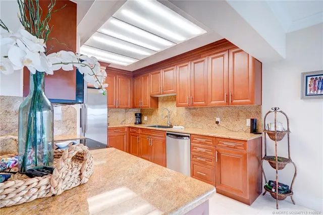 a kitchen with stainless steel appliances granite countertop a stove top oven a sink dishwasher a dining table and chairs with wooden floor