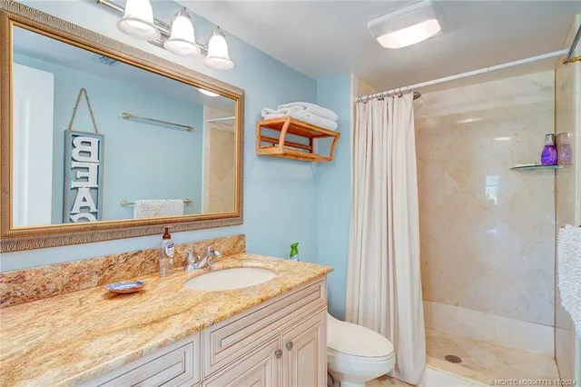 a en suite bathroom with a granite countertop sink and a mirror