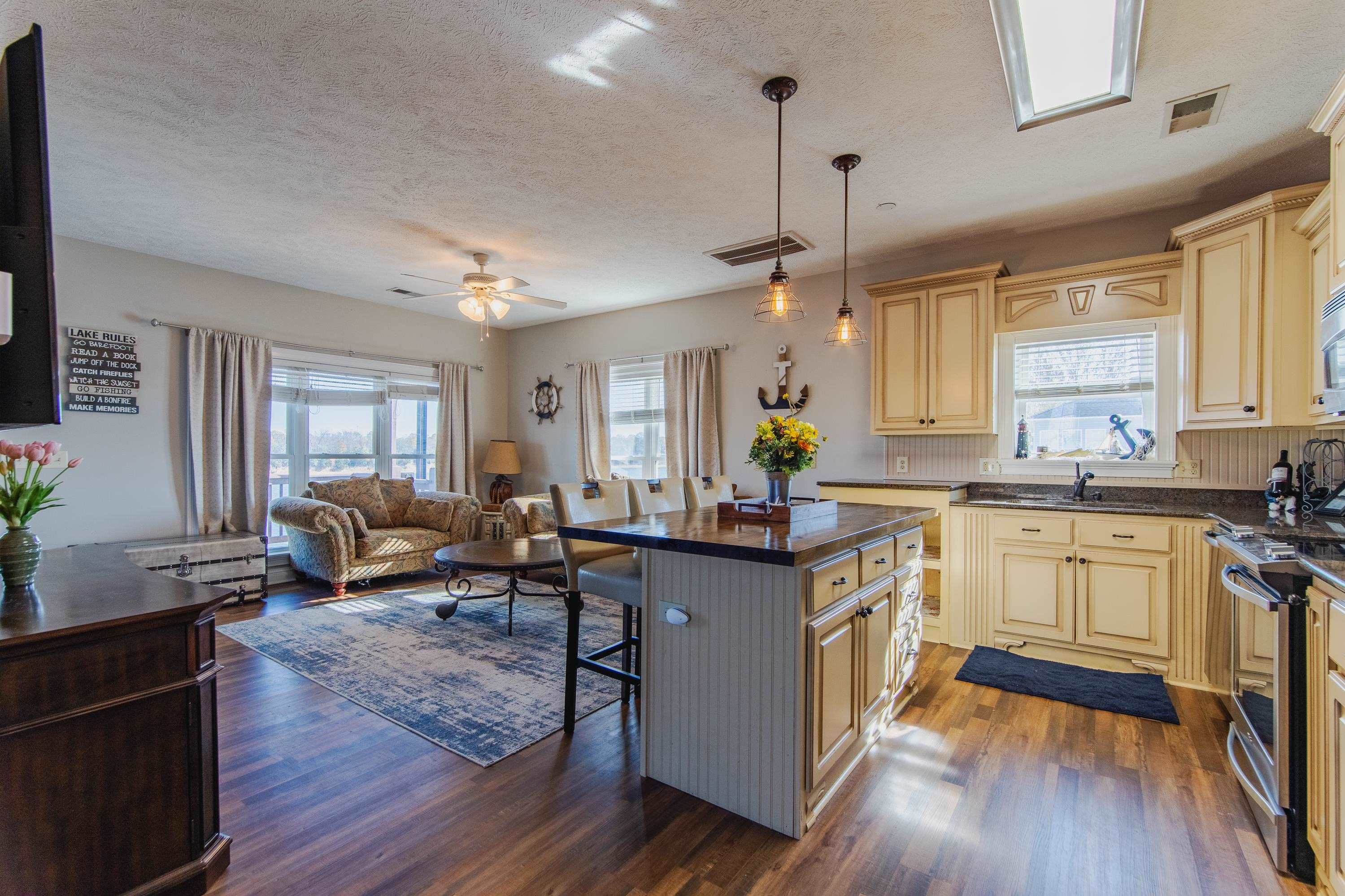 1111 Leaning Trees Lane Adamsville, TN 38310 - Photo 3 of 36 Kitchen featuring a center island, dark wood-type flooring, a kitchen breakfast bar, hanging light fixtures, and stainless steel stove