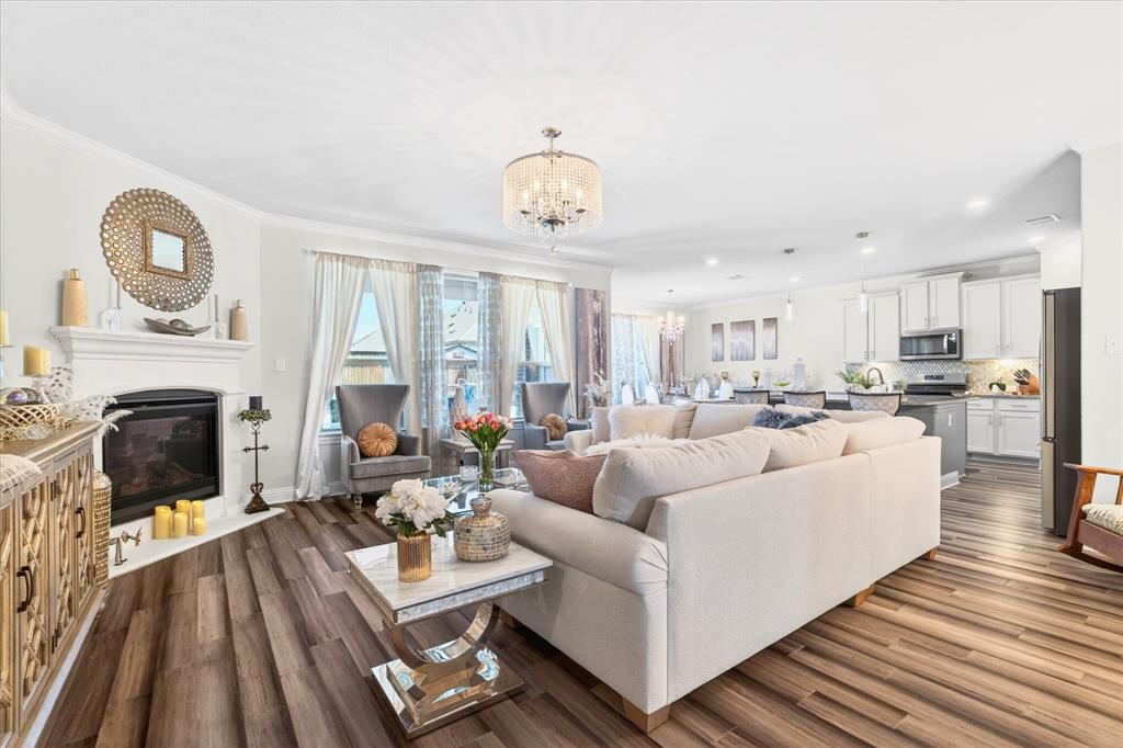 2816 Permian Road Aubrey, TX 76227 - Photo 4 of 36 Living room with suspended lighting, a fireplace with flush hearth, and dark wood-type flooring