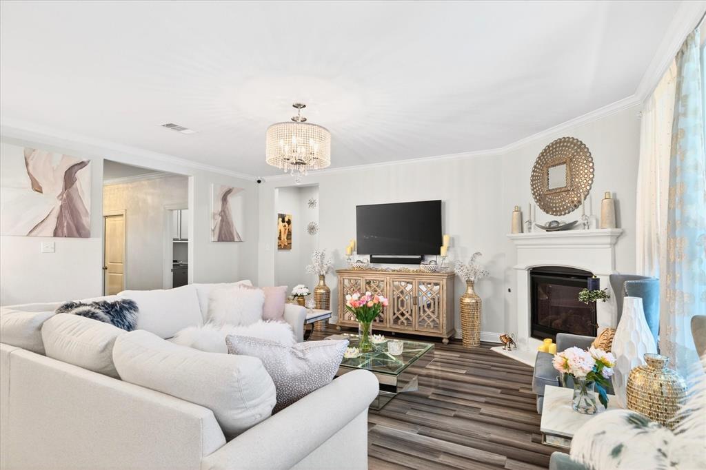 2816 Permian Road Aubrey, TX 76227 - Photo 10 of 36 Living area with ornamental molding, hanging lights, wood finished floors, and a fireplace with flush hearth