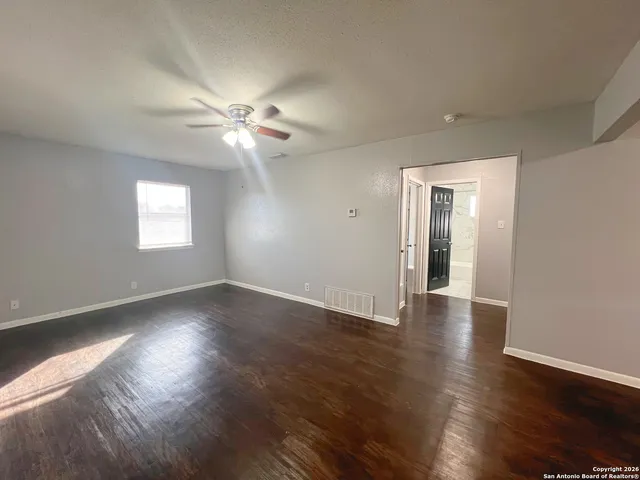a view of an empty room with wooden floor and a window