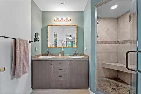 a bathroom with a sink a mirror a vanity and a shower