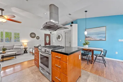 a kitchen with stainless steel appliances granite countertop a stove and a view of living room