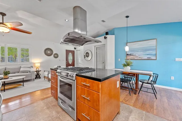 a kitchen with stainless steel appliances granite countertop a stove and a view of living room