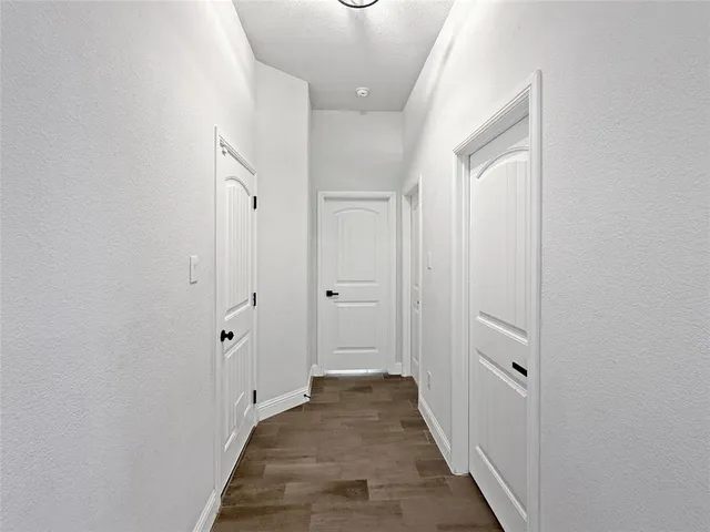 a view of a hallway with wooden floor and a bathroom