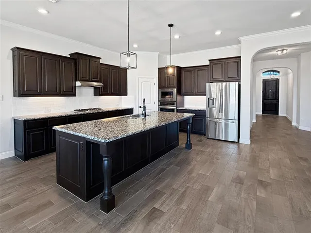 a kitchen with stainless steel appliances granite countertop a stove a refrigerator and a sink