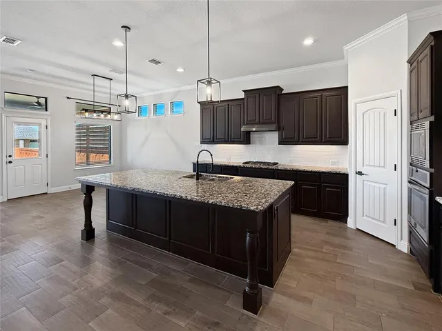 a kitchen with kitchen island granite countertop a sink a counter top space stainless steel appliances and cabinets