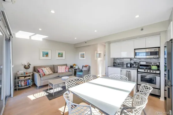 a living room with stainless steel appliances furniture a rug and a kitchen view