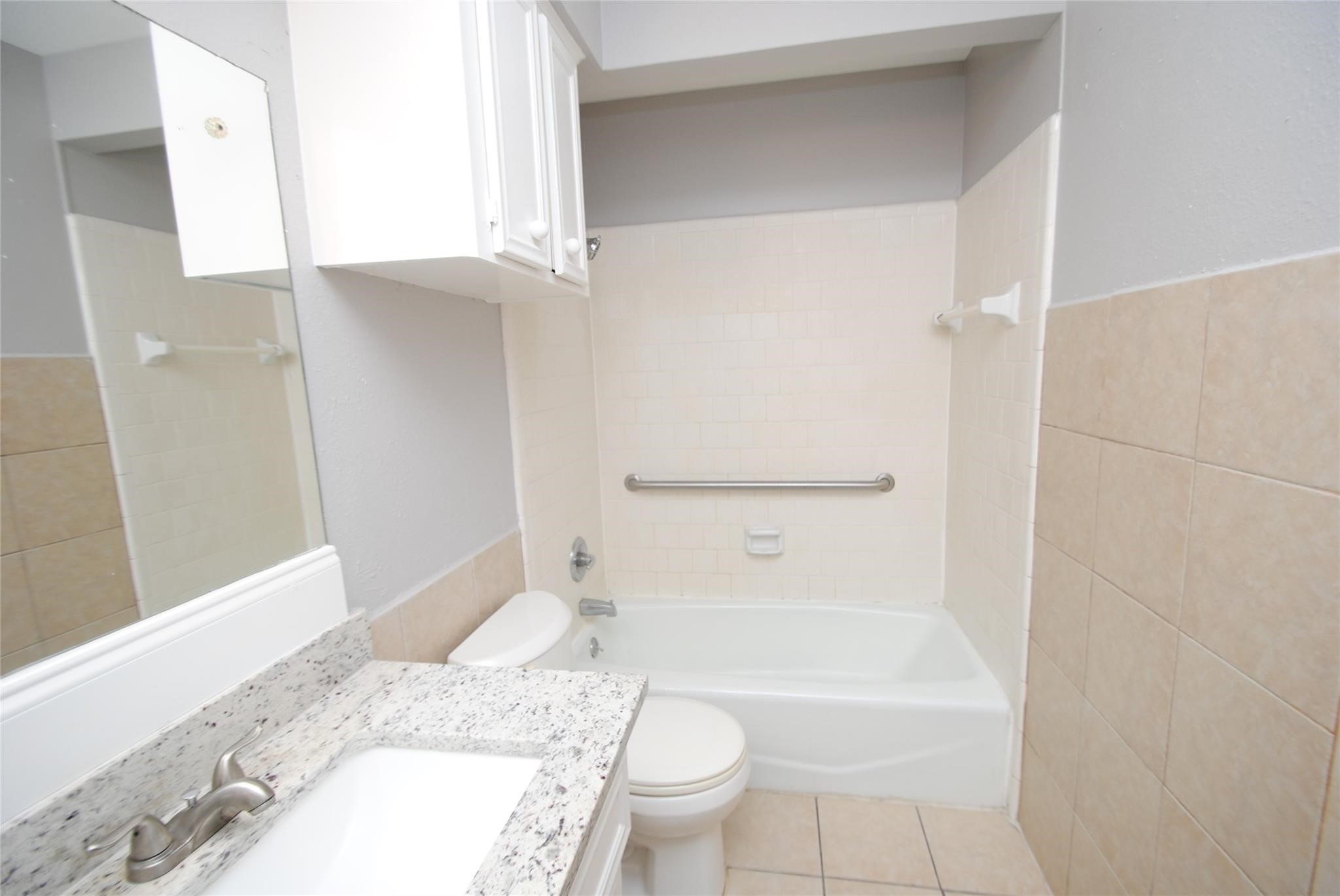12802 Newbrook Drive Houston, TX 77072 - Photo 12 of 17 a bathroom with a granite countertop toilet a sink and a bathtub