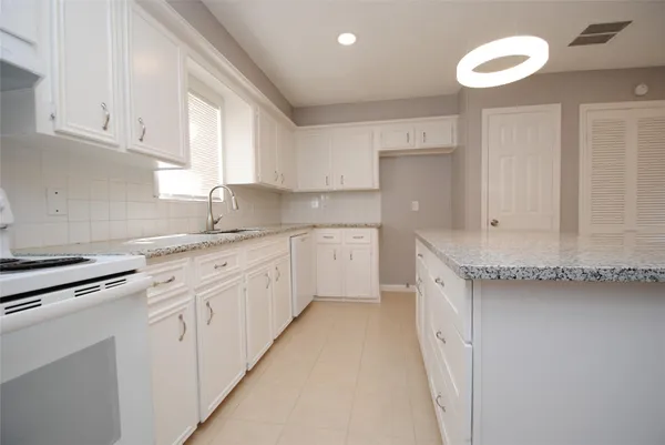 a kitchen with granite countertop white cabinets and white appliances