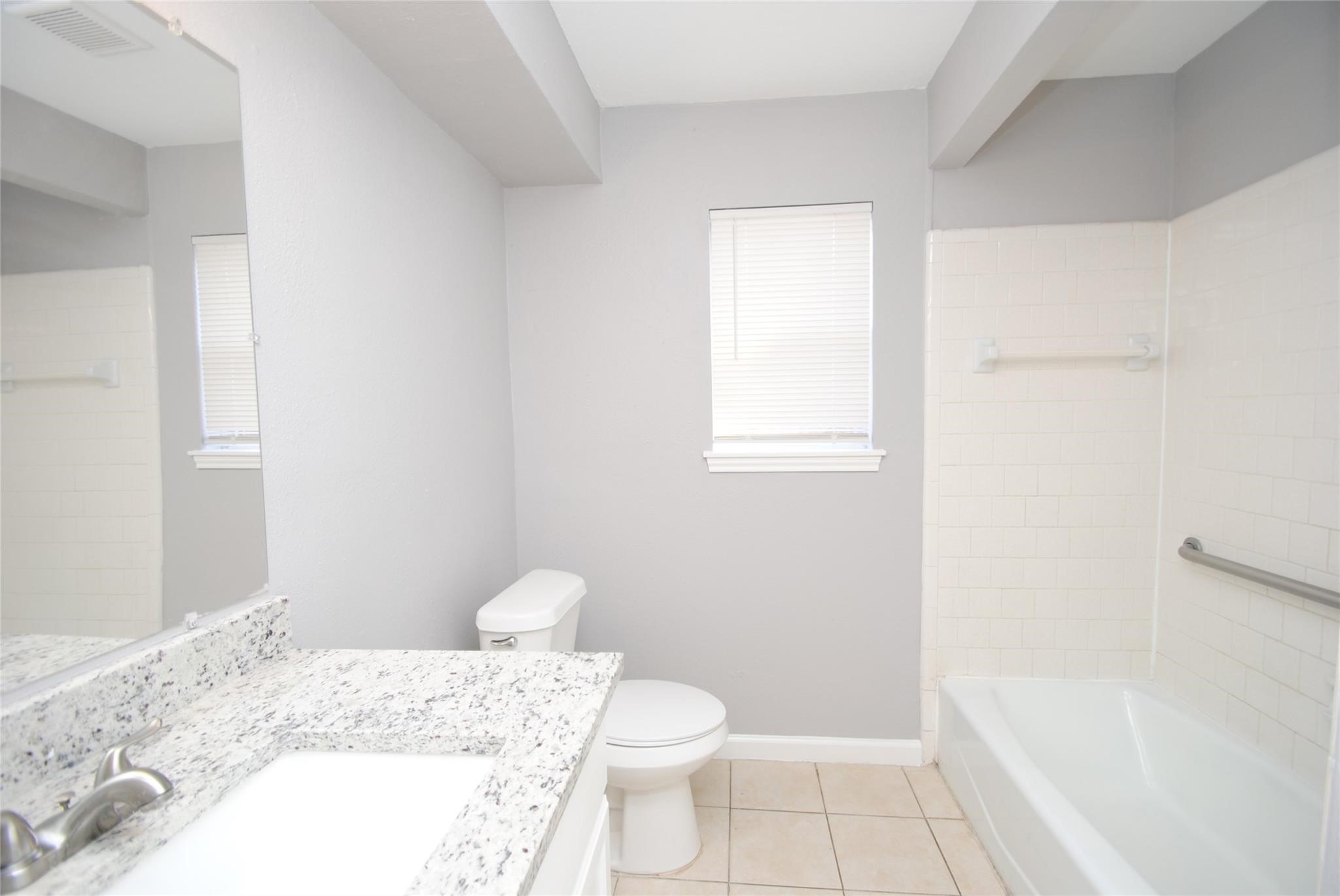 12802 Newbrook Drive Houston, TX 77072 - Photo 9 of 17 a bathroom with a granite countertop sink a toilet and shower