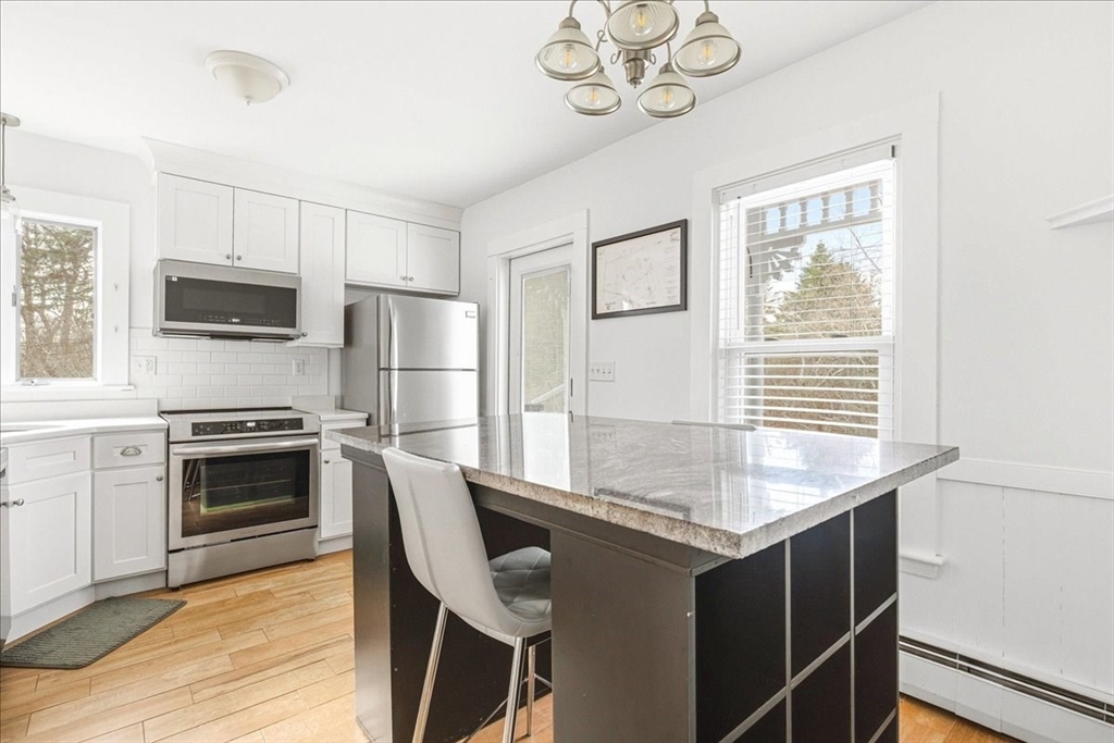 16 Howard Avenue Holbrook, MA 02343 - Photo 22 of 40 a kitchen with kitchen island granite countertop a stove a sink dishwasher a refrigerator cabinets and dining table