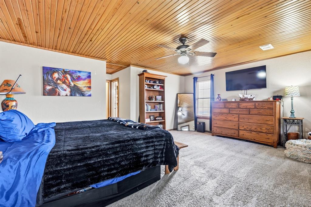 309 Sanders Road Denton, TX 76210 - Photo 14 of 40 a spacious bedroom with a bed a dresser and a book shelf
