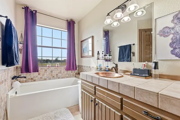a bathroom with a granite countertop sink mirror and a bathtub