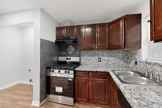 a kitchen with granite countertop a stove sink and cabinets