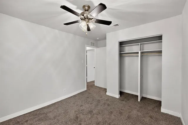 an empty room with a ceiling fan and closet
