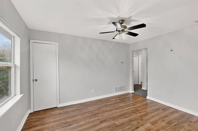 a view of empty room with wooden floor and fan