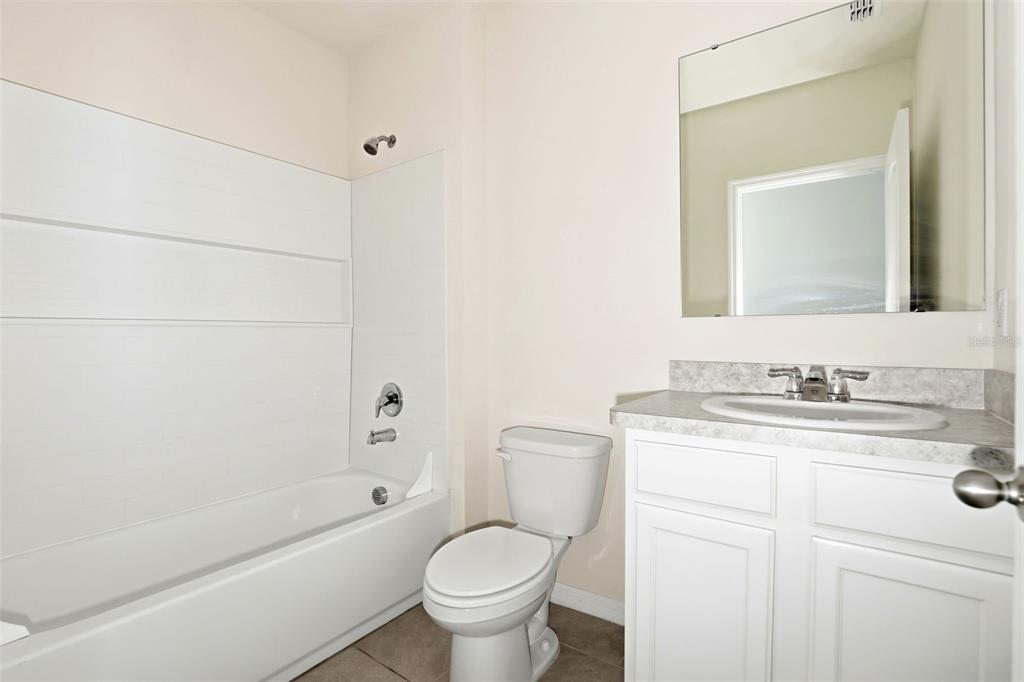 6777 Huntleigh Hammock Road Harmony, FL 34773 - Photo 19 of 32 a bathroom with a granite countertop toilet a sink and a bathtub