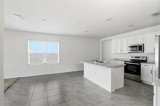 a kitchen with stainless steel appliances granite countertop a stove top oven a sink a microwave and a refrigerator