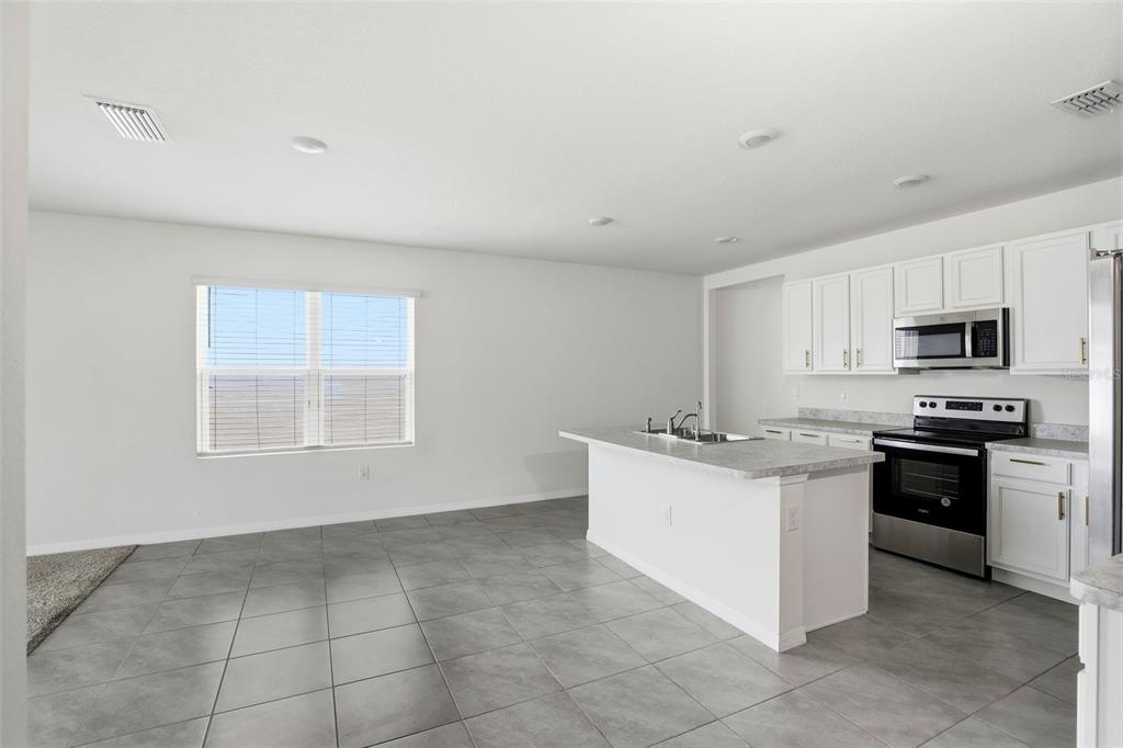 6777 Huntleigh Hammock Road Harmony, FL 34773 - Photo 8 of 32 a kitchen with stainless steel appliances granite countertop a stove top oven a sink a microwave and a refrigerator