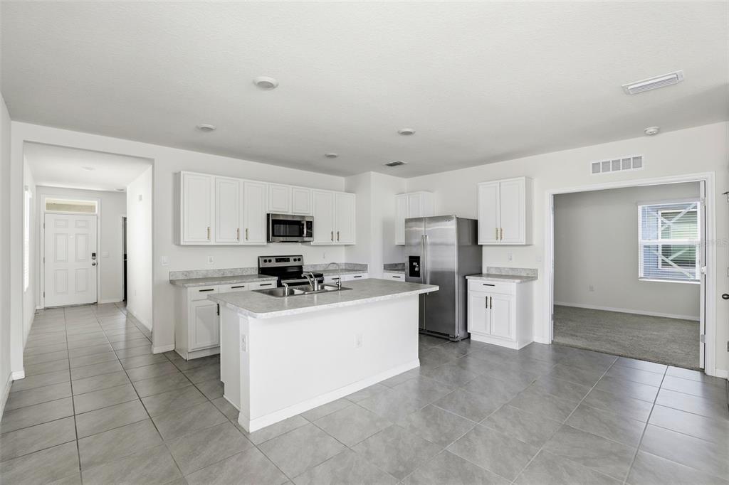 6777 Huntleigh Hammock Road Harmony, FL 34773 - Photo 10 of 32 a kitchen with stainless steel appliances a refrigerator stove and sink