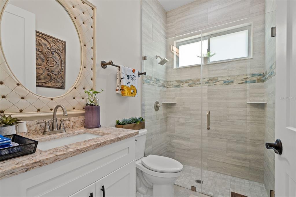 17601 Hanna Road Lutz, FL 33549 - Photo 32 of 48 a bathroom with a granite countertop sink a toilet a mirror and shower