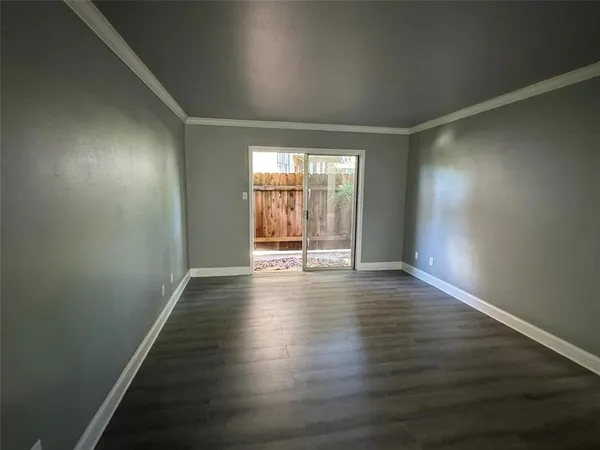 an empty room with wooden floor and windows with curtains