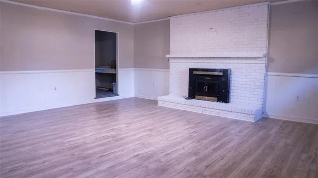a view of an empty room with wooden floor and a fireplace