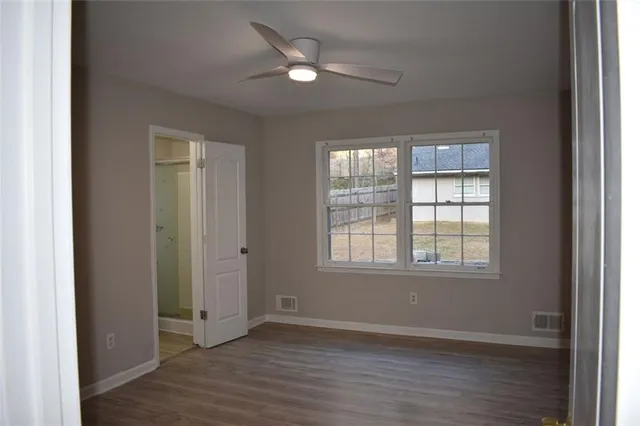 an empty room with wooden floor and windows