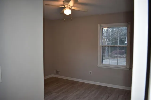 an empty room with wooden floor closet and windows