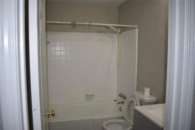 a bathroom with a granite countertop toilet a sink and shower