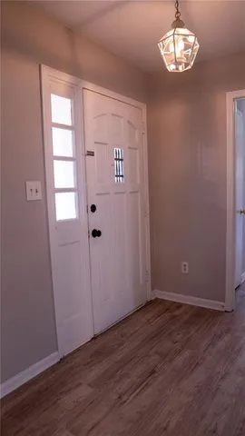 an empty room with wooden floor cabinet and windows