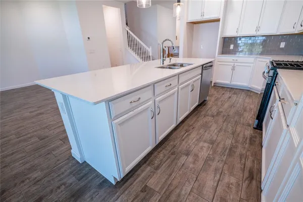 a large white kitchen with kitchen island a stove a sink dishwasher and a large refrigerator
